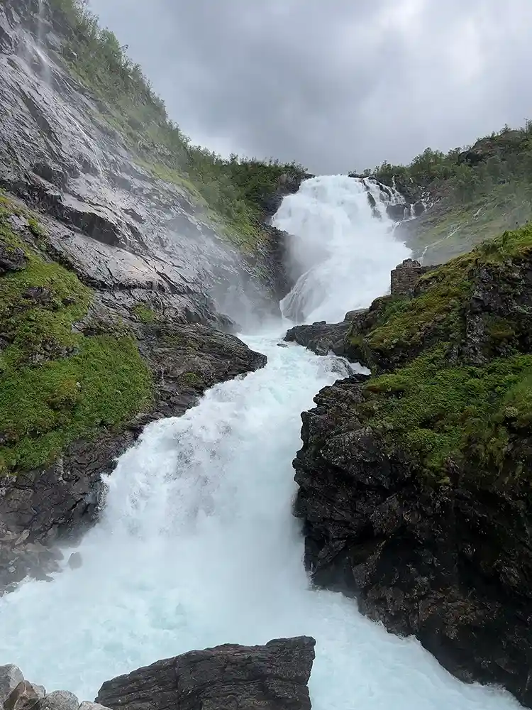 En foss som strømmer ned siden av et fjell i naturen. Sett nedenfra. Vardar AS
