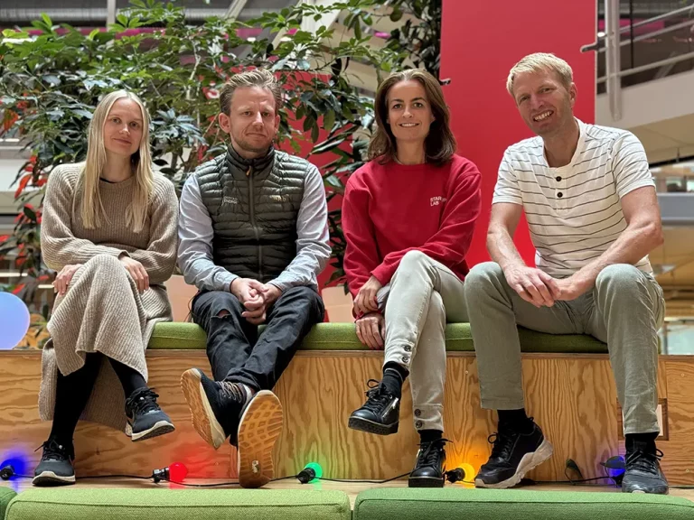 fire personer sitter op en benk med planter rundt seg